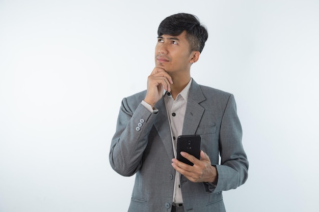 Een man in een grijs pak houdt een zwarte telefoon in zijn hand en kijkt naar het scherm