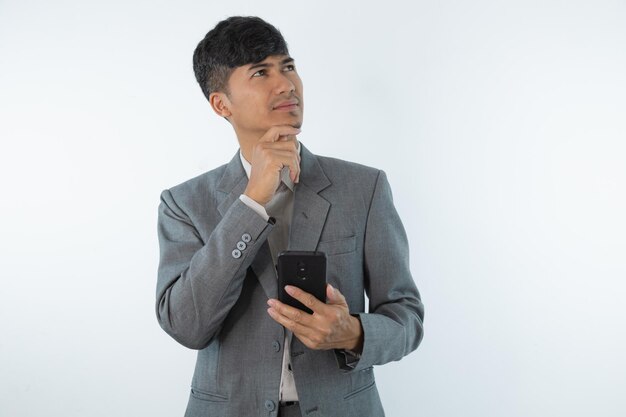 Een man in een grijs pak houdt een zwarte telefoon in zijn hand en kijkt naar het scherm