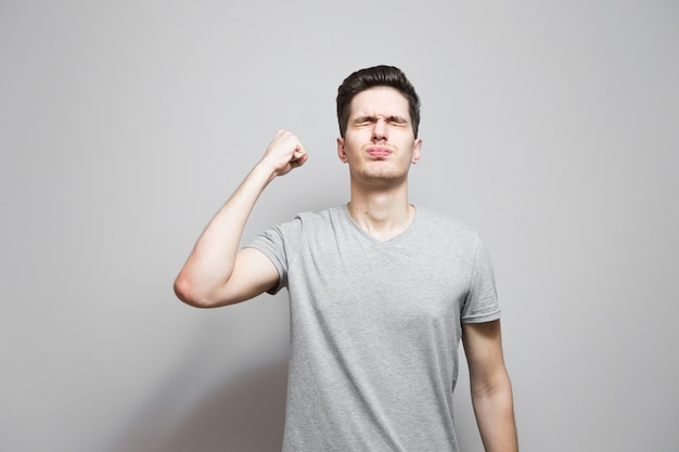 Een man in een grijs T-shirt met emoties op zijn gezicht.