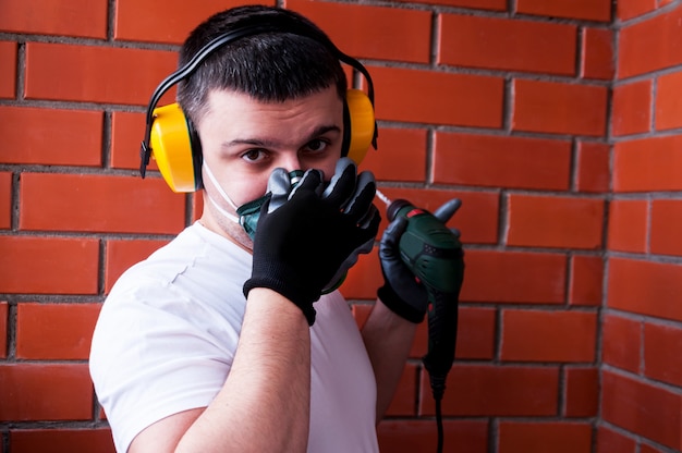 Een man in een helm en een gasmasker voert schilderwerk uit op een betonnen plafond