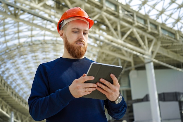 Een man in een helm in een grote ruimte met een tablet