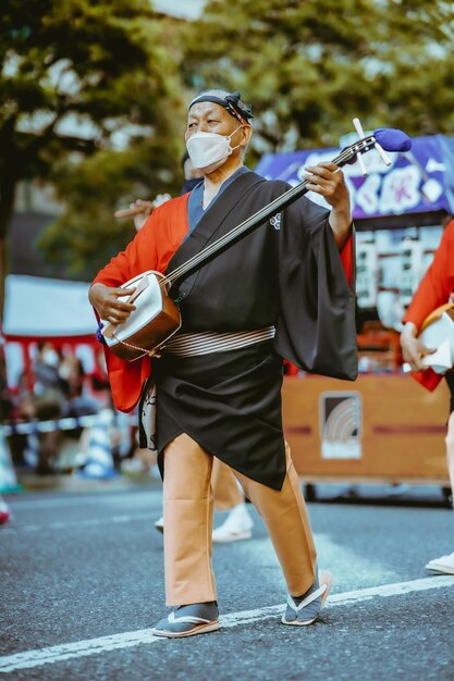 Foto een man in een kimono speelt op een tamboerijn in een straat.