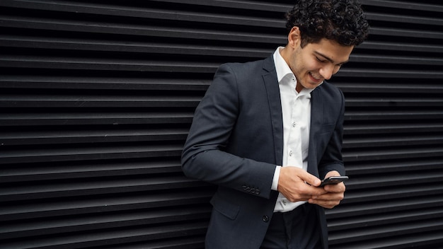 Een man in een officieel pak houdt een telefoon in zijn handen en schrijft een bericht