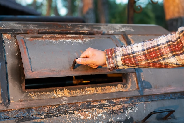 Een man in een overhemd met stroken kijkt naar een uitstekende professionele grill voor het opnieuw bakken van vlees Professionele buitenbarbecue