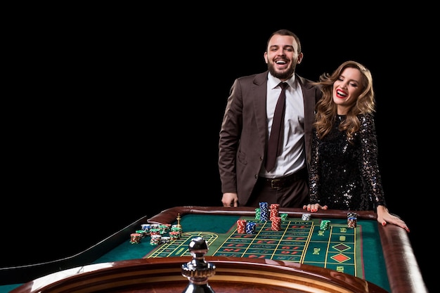 Een man in een pak met een vrouw in een mooie zwarte jurk die roulette speelt in het casino. Gokken. Casino. Roulette. Poker.