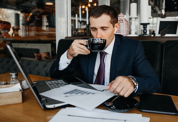 Een man in een pak werkt op een laptop in een café. Zakenman met laptop.