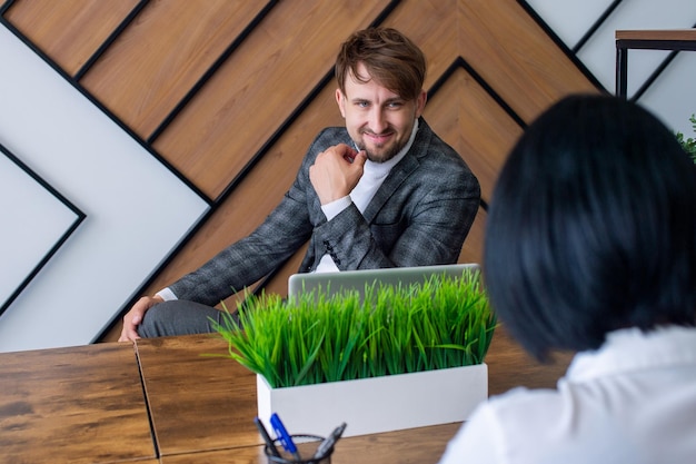 Een man in een pak zit op zijn werkplek en lacht met collega's