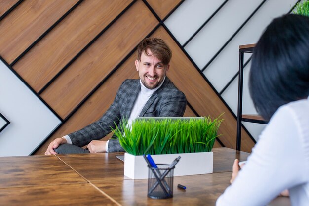 Een man in een pak zit op zijn werkplek en lacht met collega's