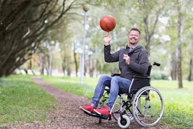 Een man in een rolstoel draait de bal op zijn vinger in het park close-up wazig paralympisch