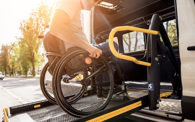 Een man in een rolstoel op een lift van een voertuig voor mensen met een handicap.