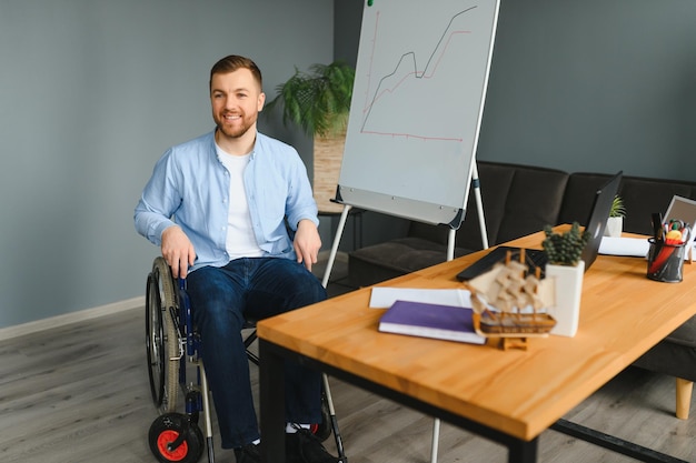 Een man in een rolstoel werkt in een kantoor Het concept van werk van mensen met een handicap