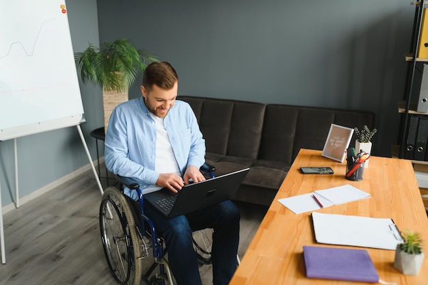 Een man in een rolstoel werkt in een kantoor het concept van werk van mensen met een handicap