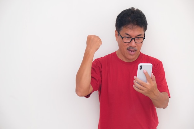 Een man in een rood t-shirt die een videogesprek voert en glimlacht