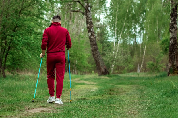 Een man in een trainingspak houdt zich bezig met nordic walking