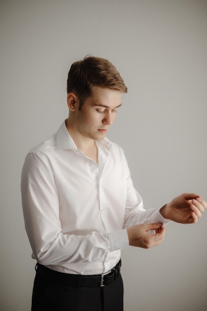 Een man in een wit overhemd kijkt naar zijn mouwen.