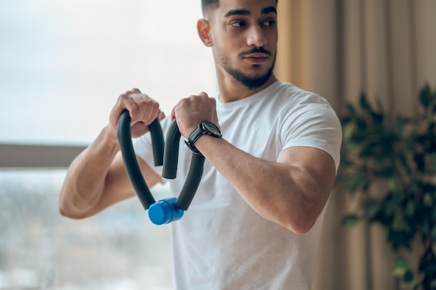 Een man in een wit t-shirt die traint met expander