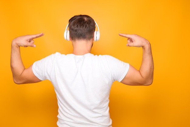 Foto een man in een wit t-shirt staat met zijn rug en luistert naar muziek, terwijl hij goed danst.