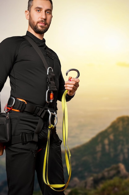 Een man in een zekeringssysteem voor werken op hoogte Karabijnhaken riemen veiligheidstouwen bergbeklimmen