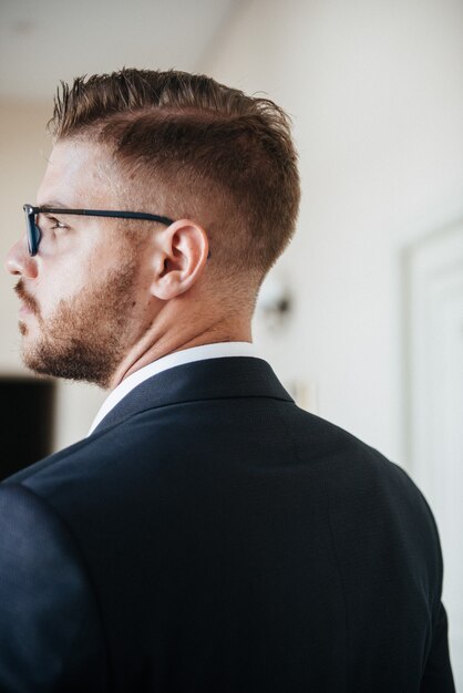 Een man in een zwart pak en een wit shirt poseert binnenshuis voor reclame voor herenkleding. Schieten voor herenkledingwinkel