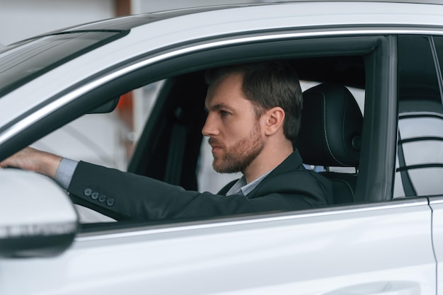Een man in formele zakelijke kleding zit in de moderne auto.