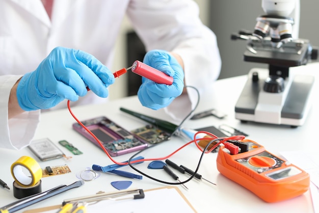 Een man in uniform met voltmeter en een rode batterij in zijn handen