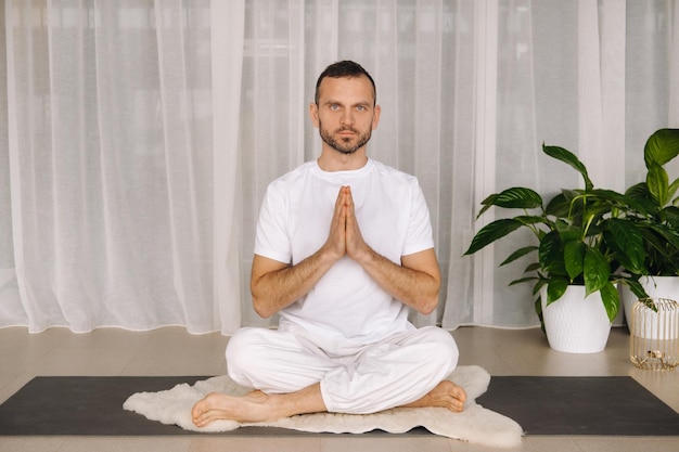 Een man in witte sportkleding doet yoga met een fitnessruimte, het concept van een gezonde levensstijl