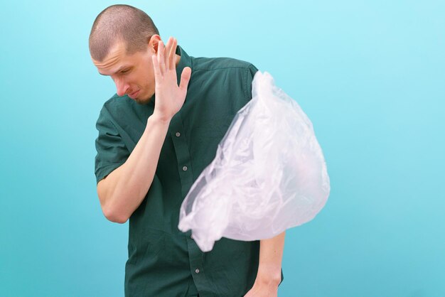 Een man keert zich af van een vliegende plastic zak op een blauwe achtergrond Recycle Recycling Stop afval Geen wegwerpobject Consument Aarde Ecologisch Menselijk probleem Product Detailhandel