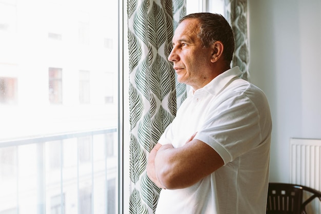 Een man kijkt uit een raam naar een hotelkamer