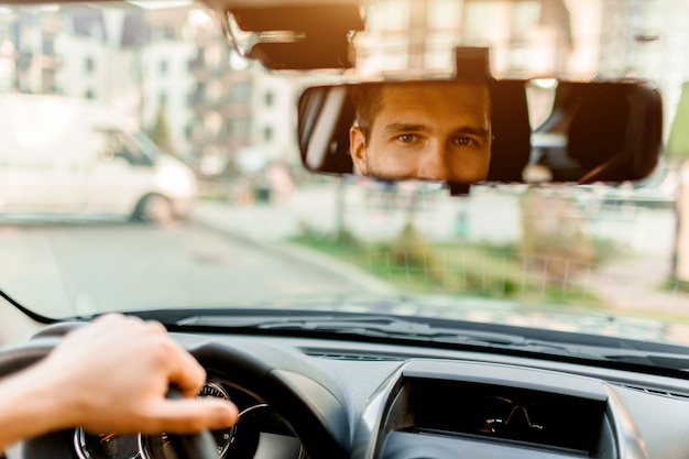 Een man kijkt uit het achterruit. In zijn auto. Vervoer concept