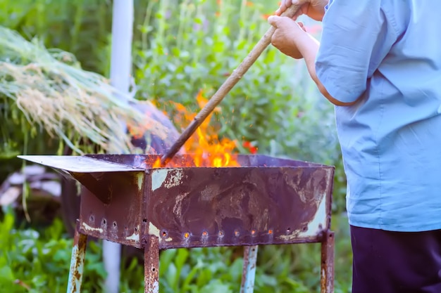 Een man kookt vuur in een metalen grill.