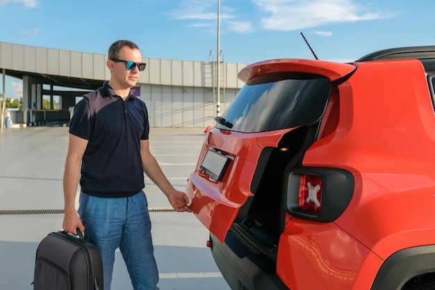 Een man laadt een koffer in de kofferbak van een auto