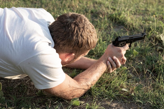 Een man ligt op het gras met een pistool in zijn handen en bereidt zich voor om te schieten vrije tijd en hobby's