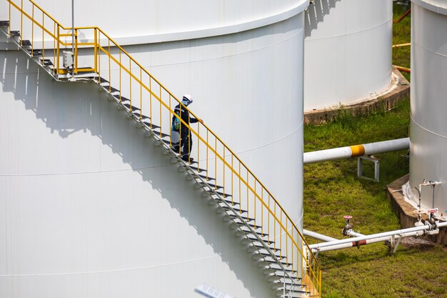 Een man loopt boven de inspectie-opname van de olietrap van de opslagtank op de zijkant van de schaalplaat