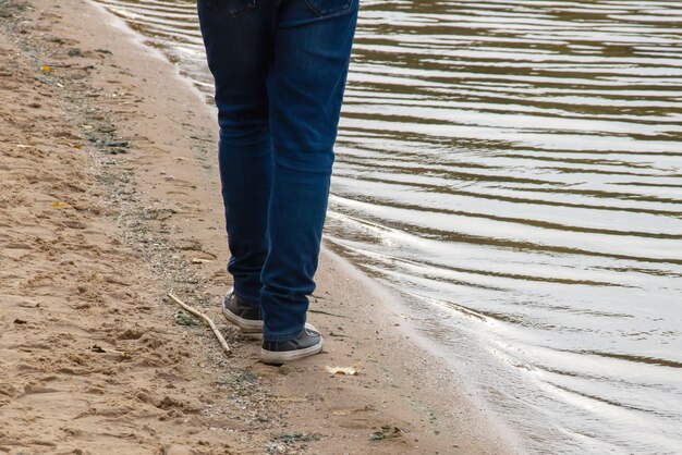 Een man loopt langs de zanderige oever van de rivier