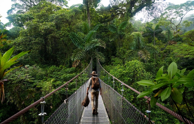 Een man loopt over een brug in de jungle.