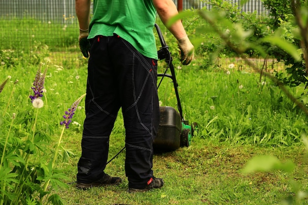 Foto een man maait het gras met een grasmaaier in de tuin