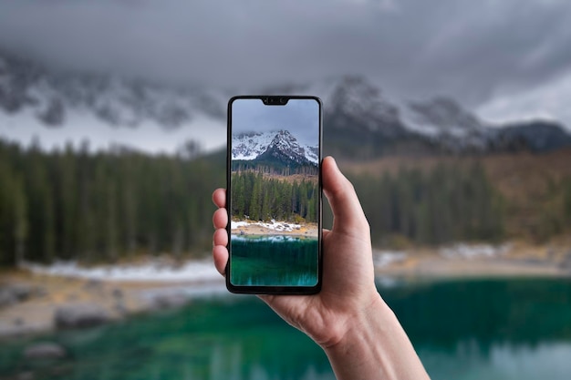 Een man maakt een foto op een smartphone prachtig landschap van Lake Carezza met Mount Latemar Bolzano provincie Zuid-Tirol Italië