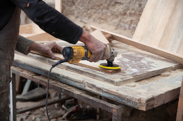 Een man maalt hout met een schuurmachine timmerman werkt met een hout