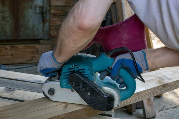 Een man maalt houten planken met een slijper Houtbewerking timmerwerk hobby