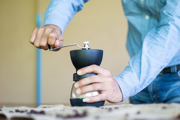 Een man maalt koffiebonen met een handmixer.