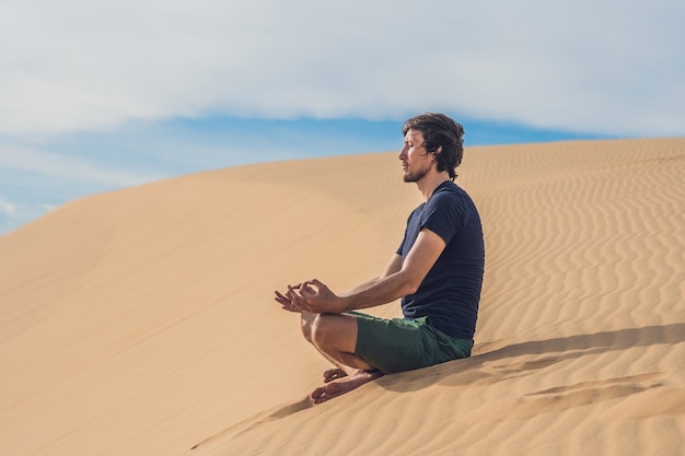 Een man mediteert op het zand in de woestijn.