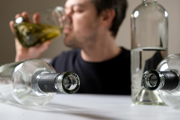 Een man met alcoholverslaving drinkt pekel uit een pot aole komkommers een man met een kater