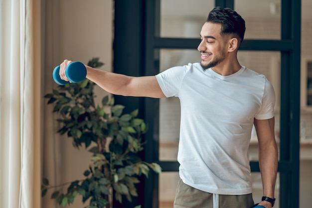 Een man met dumbbells die thuis traint