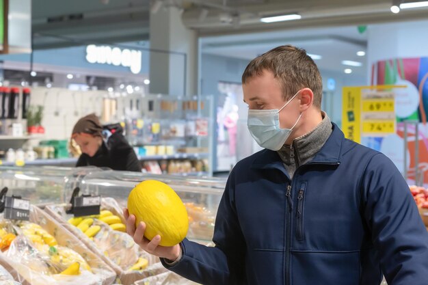 Een man met een beschermend gezichtsmasker met een meloen in zijn hand Quarantaine Lifestyle Eten en drinken