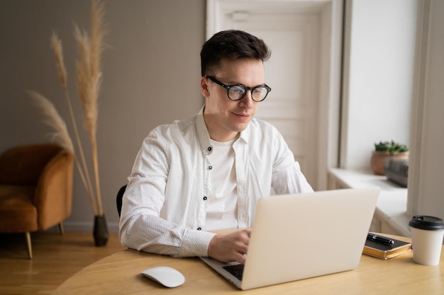 Een man met een bril gebruikt een laptopcomputer op kantoor
