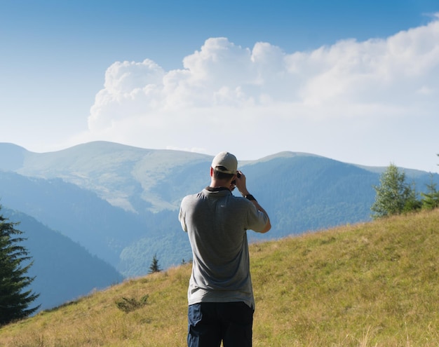 Een man met een camera op de achtergrond van een berglandschap.