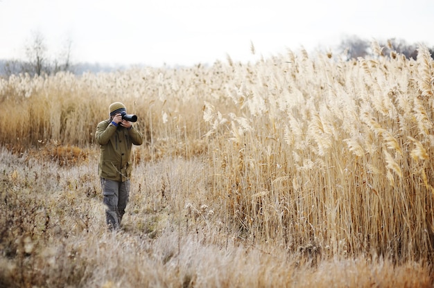 Een man met een camera op een achtergrond van geel hoog gras. Fotograaf landschap