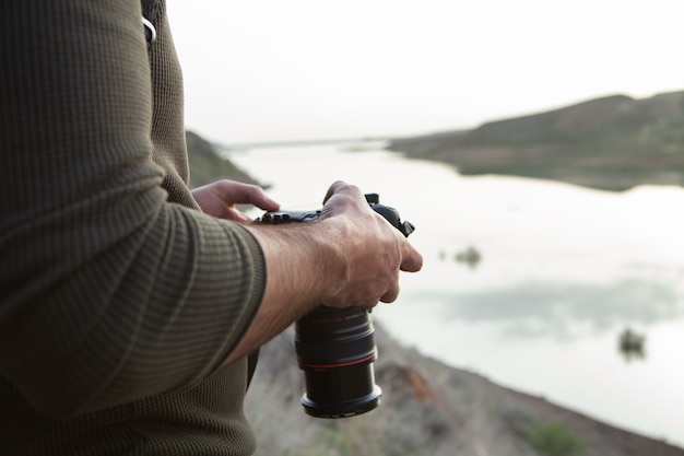 Een man met een camera staat 's avonds aan het meer