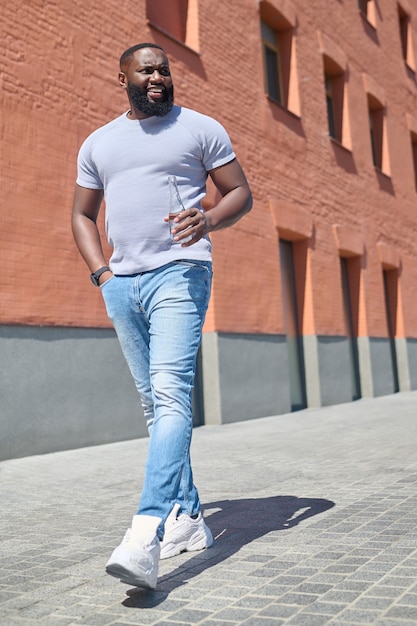 Een man met een donkere huidskleur in een wit t-shirt die op straat loopt