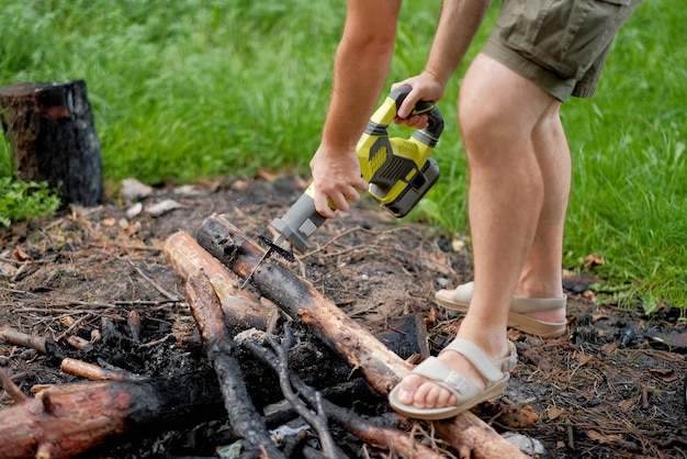 Een man met een elektrische zaag die het brandhout in het bos zaagt. Een medewerker van een houtzagerij zaagt hout